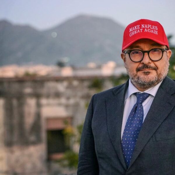 «Make Naples great again»: Sangiuliano lancia il berretto trumpiano. Poi trova al ristorante Angela Merkel e cantano “Funiculì funiculà“